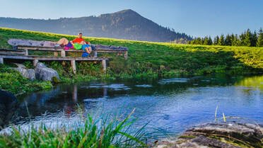 Paar beim Relaxen auf Bank, Ursprungsquelle | © TVB Naturpark Zirbitzkogel-Grebenzen